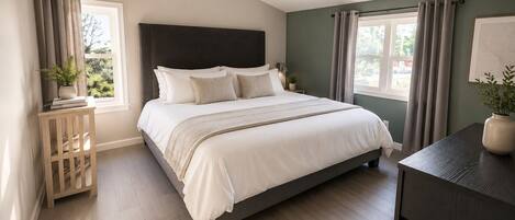 A bedroom with a bed, bedside tables, a dresser, and a window with curtains.