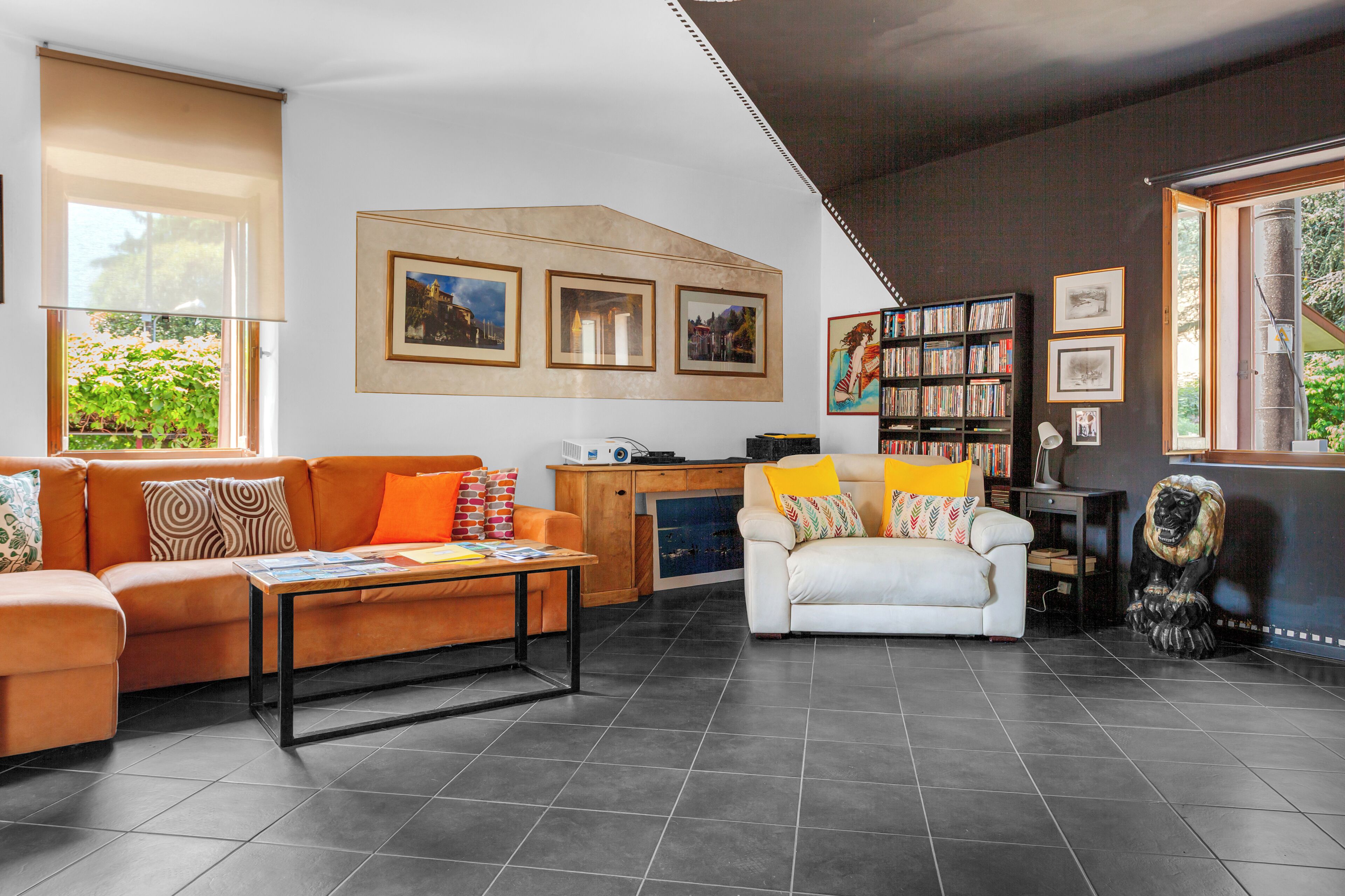 Un salon moderne avec un canapé, une table basse et un fauteuil blanc. On y trouve également une bibliothèque et une sculpture décorative.