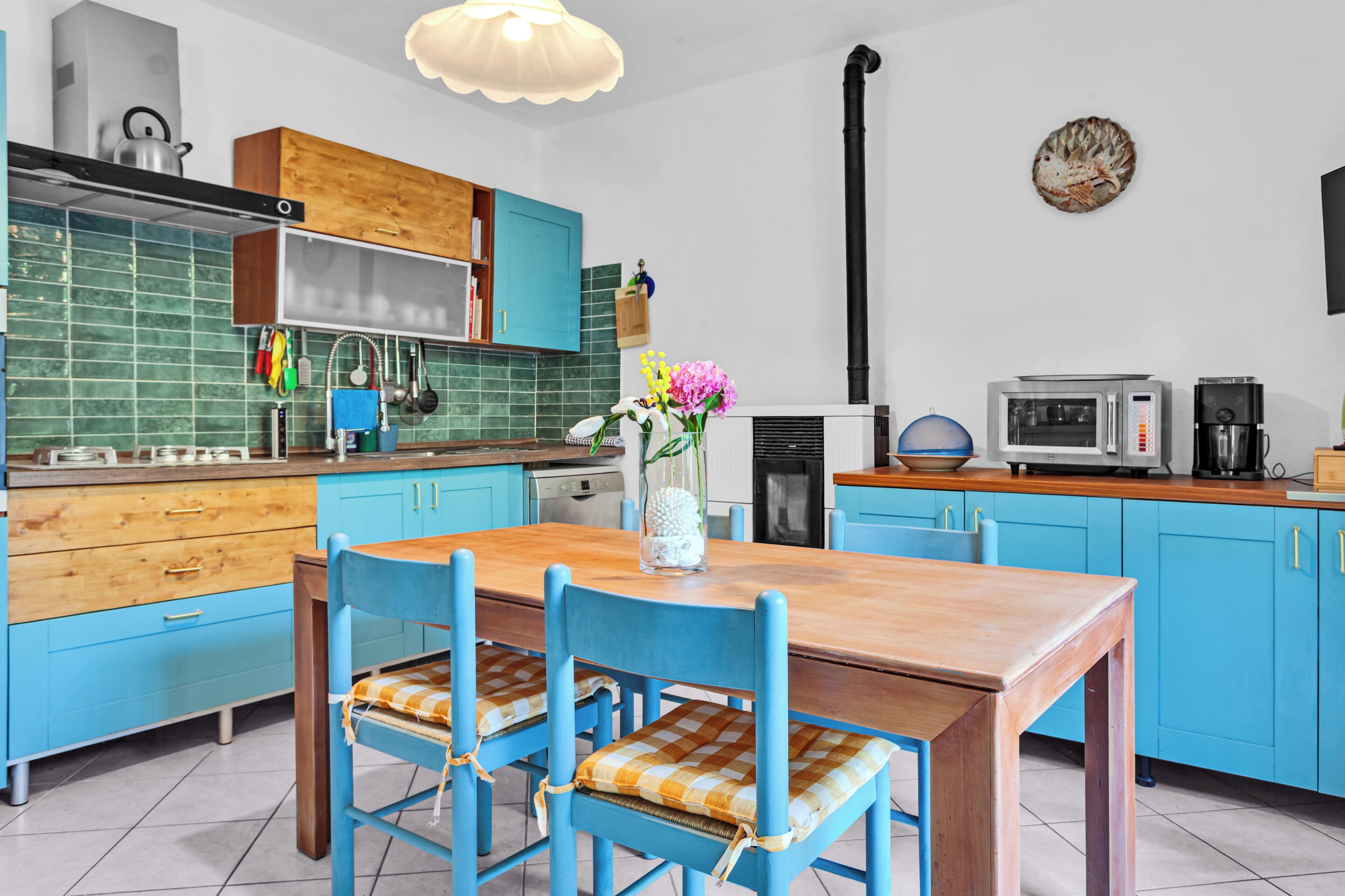 Una cucina moderna con mobili blu, un tavolo da pranzo in legno e sedie con cuscini a quadri.