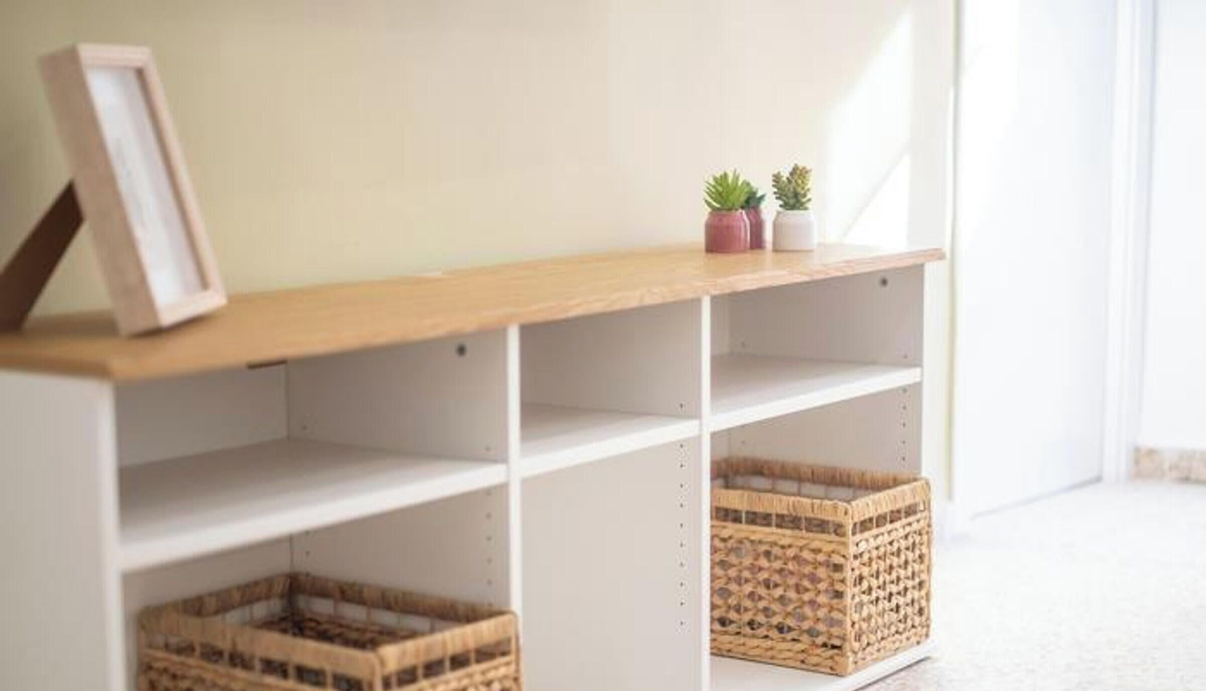 A room with a wooden shelf, two small potted plants, and wicker baskets.