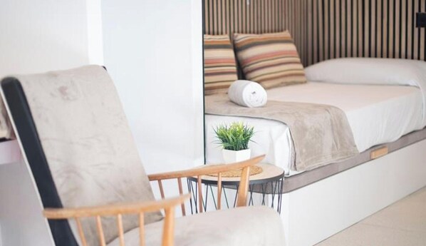 A modern bedroom with a bed, a chair, a small table with a plant, and a wall-mounted heater. - Detached house in Tarragona's historic center (Tarragona)