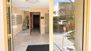 A hotel entrance with a reception desk, a staircase leading to the parking area, and a view of the street outside. - Charming T2 with sea view - 2 guests (Argelès-sur-Mer)