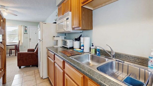 Una cocina compacta con armarios de madera, microondas, fregadero y comedor con una silla y una mesa.