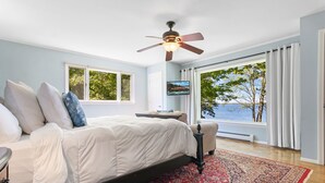 Quarto com cama, ventilador de teto, televisão e vista para o exterior.