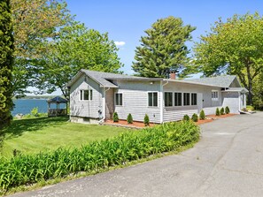 A single-story house with a porch, a small deck, and a view of the water. - Charming Home With Stunning bay Views, Sunroom, Gazebo, Deck, & Grill (Trenton)
