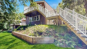 Une maison avec une terrasse en bois, un escalier et un jardin.