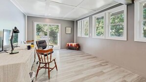 Une pièce spacieuse avec une grande fenêtre, un bureau avec une chaise et une petite table avec une chaise.