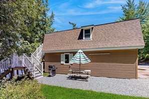 A single-story wooden cabin with a covered patio, a small window, and a deck. - Heart Pond Hideaway (Orland)