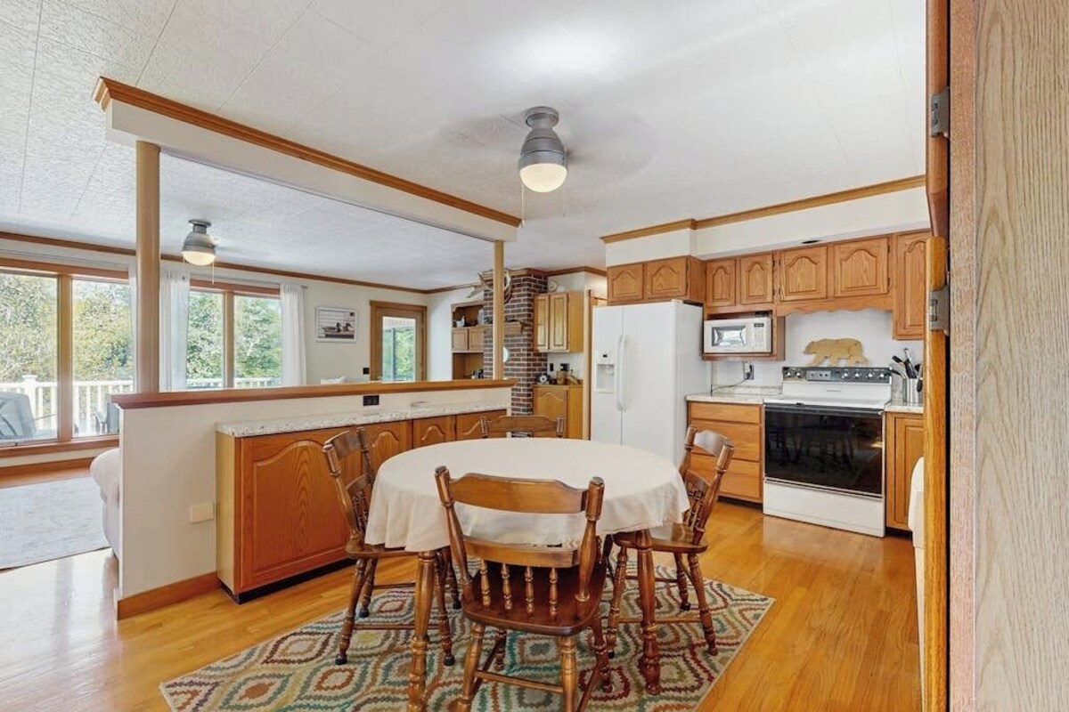 A kitchen with wooden cabinets, a dining table with chairs, a refrigerator, and an oven.