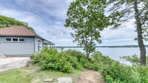 Ein Haus mit Seeblick, umgeben von Bäumen und Sträuchern.