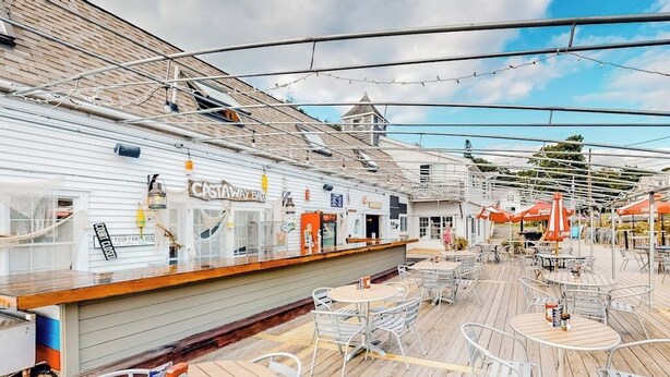 Ett däck med utomhusmöbler, en bar och en skylt med texten ”CASTAWAY BAR”.