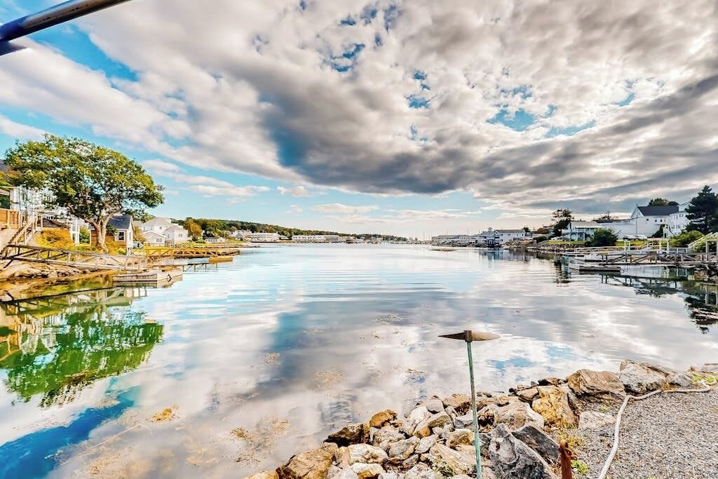 A calm waterfront with a pier, boats, and a clear sky.