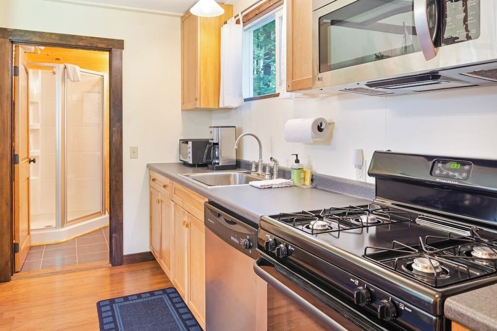 A compact kitchen with a stove, microwave, and sink.