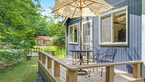 En træterrasse med et bord, stole og en stor parasol.