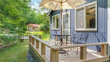 A deck with a table and chairs, a wooden railing, and a large umbrella.