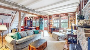 A rustic interior with exposed wooden beams, a fireplace, and a cozy seating area. - Cozy, Waterfront Cabin-style Gem With Private Dock and Lovely Views (Bath)