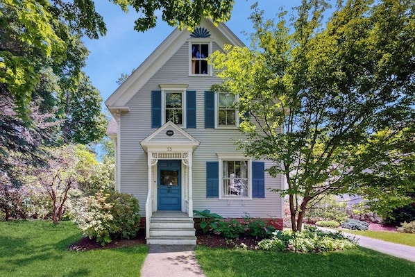 A two-story house with a front porch, a blue door, and a small garden. - Parker House: Historic Home - Walk Downtown, Dog-friendly & Washer/dryer (Camden)