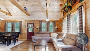 En stuga byggd av timmer med en inredning som inkluderar en matplats, en soffa, en fläkt och en julgran.