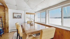 Zona pranzo con tavolo in legno, sedie e vista sull'esterno.