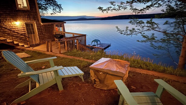 Una baita sul lago con una terrazza, posti a sedere all'aperto e un tavolo da picnic coperto.