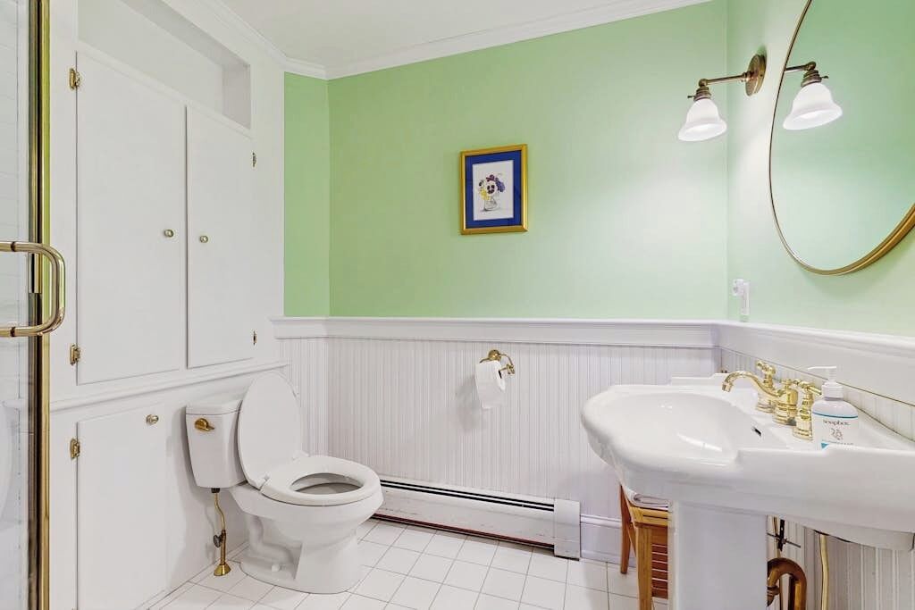 Ein Badezimmer mit Toilette, Waschbecken und einem gerahmten Bild an der Wand.
