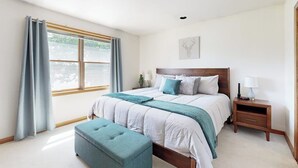 A bedroom with a bed, bedside tables, a window with curtains, and a wall-mounted artwork. - Charming Lakefront House With Outdoor Firepit, Washer/dryer and Wifi (Gouldsboro)