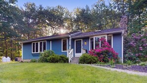 A single-story house with a front porch, a chimney, and a well-maintained lawn. - Tree-lined Home With Screened Porch & Perfect Midcoast Location (Damariscotta)