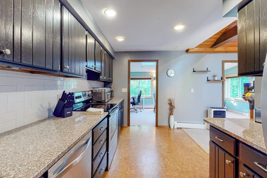 A kitchen with dark wooden cabinets, granite countertops, and stainless steel appliances.