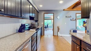 A kitchen with dark wooden cabinets, granite countertops, and stainless steel appliances. - Tree-lined Home With Screened Porch & Perfect Midcoast Location (Damariscotta)