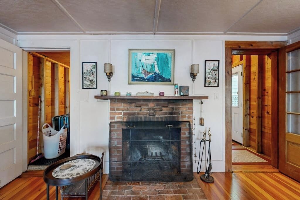 A room with a fireplace, wooden walls, and a door leading to another room.