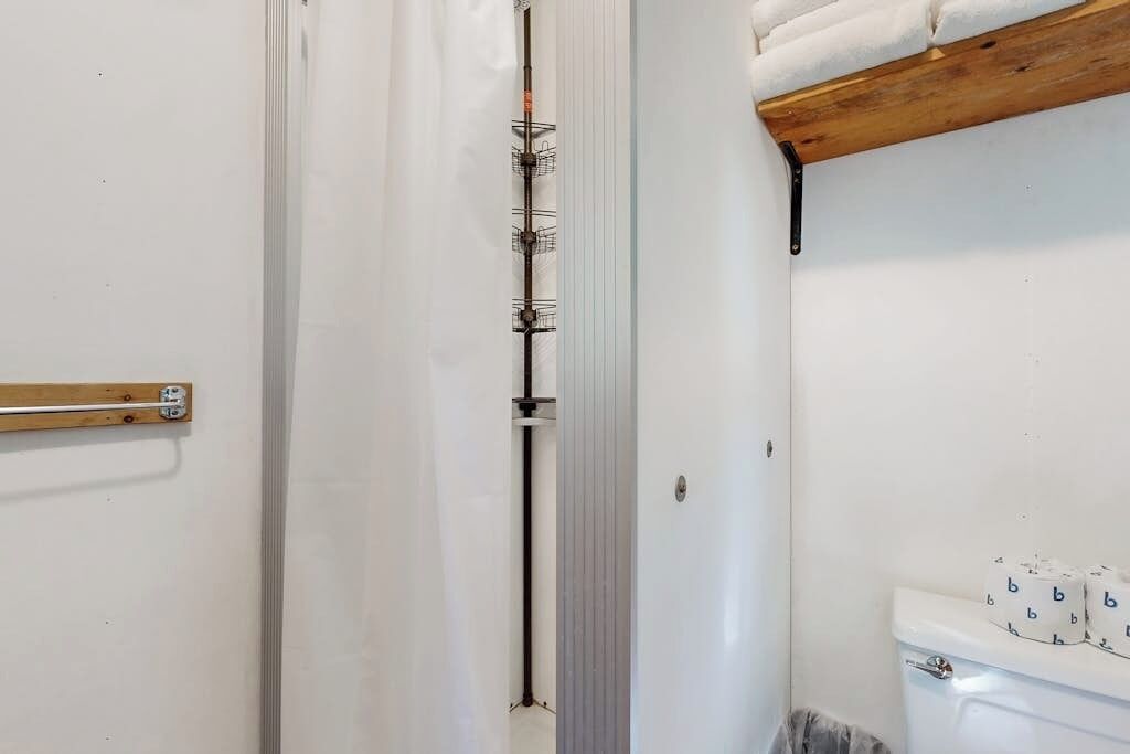 A bathroom with a white toilet, a towel rack, and a shower curtain rod.