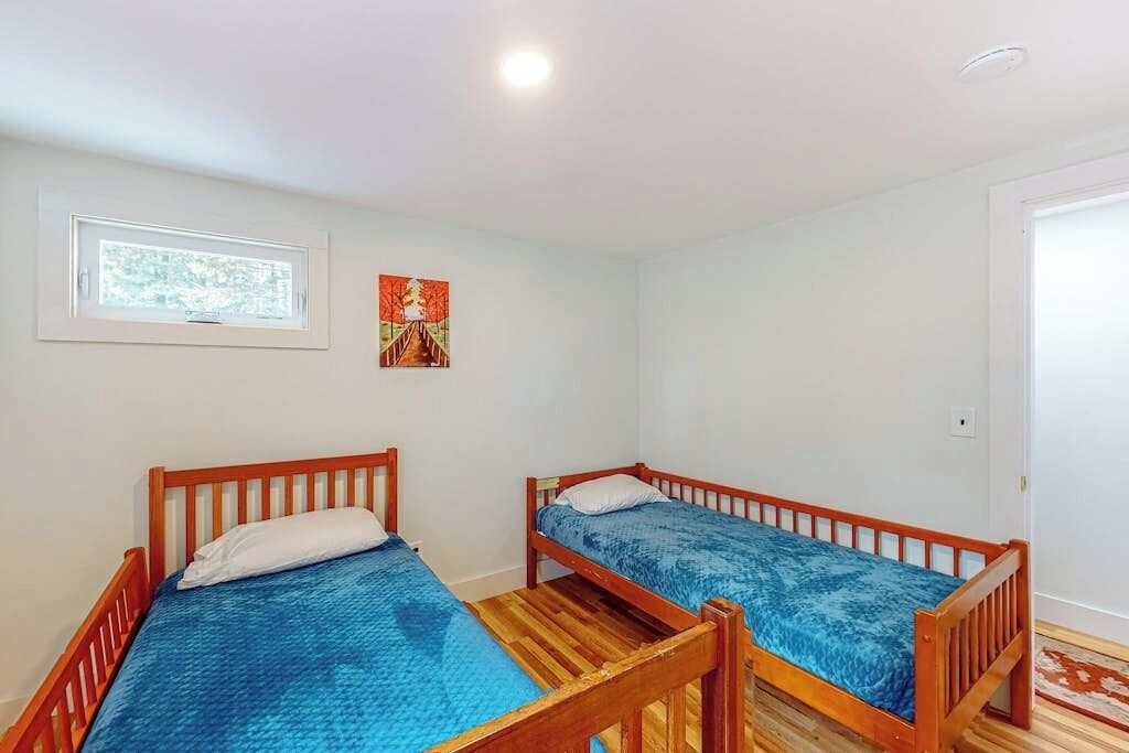 Ein Zimmer mit zwei Holzbetten, einem Fenster und einer Tür.