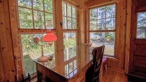 Ein Holzblock-Interieur mit großen Fenstern, einem Glastisch und einer roten Lampe.
