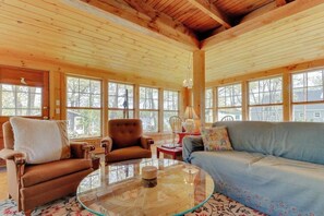 Ein Holzinterieur mit einer Couch, Sesseln und einem Glastisch.