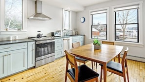A modern kitchen with a dining area, large windows, and a view of the outside. - Harborwalk (Camden)