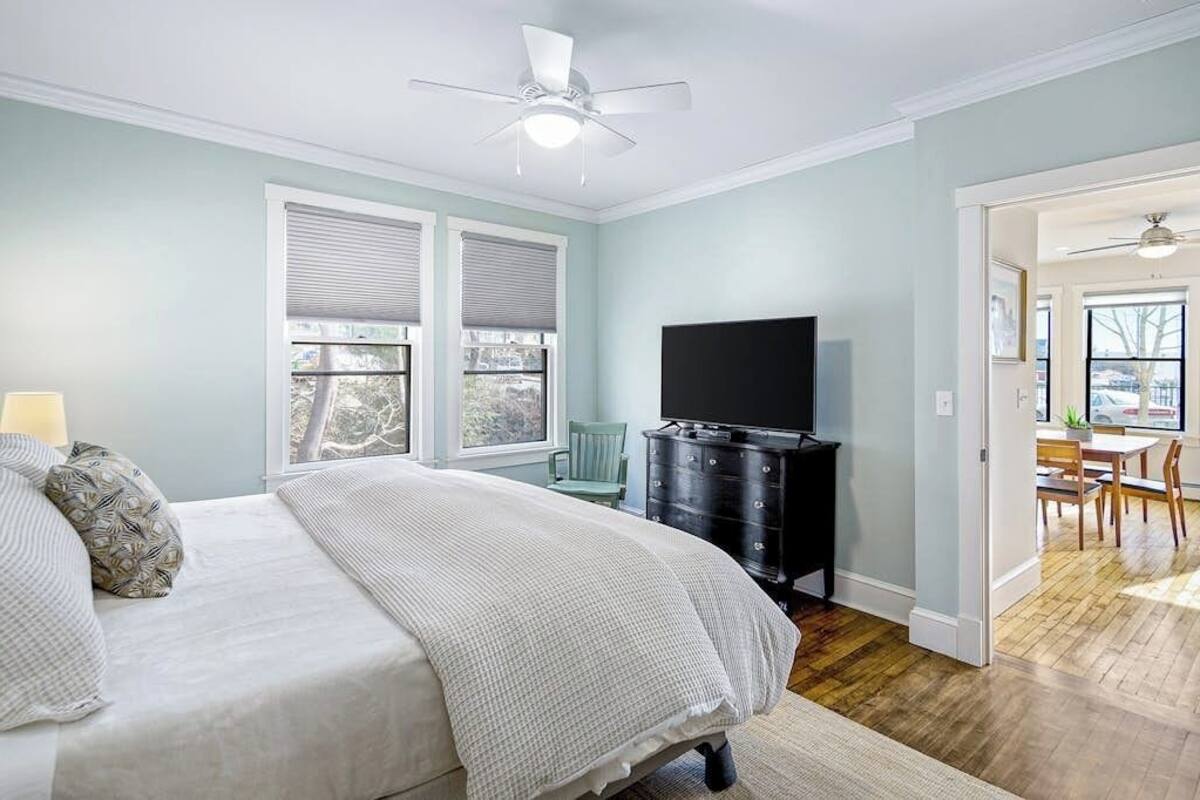 A bedroom with a bed, a dresser, a TV, and a window.