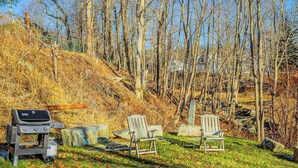 A backyard with a grill, two Adirondack chairs, and a stone wall. - Harborwalk (Camden)
