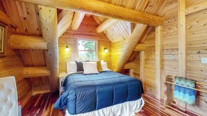 A log cabin room with a bed, wooden walls, a window, and a lamp. - Tranquil Haven Secluded Waterfront House With Sauna, Dock, Kayaks, Canoe, gym (Greenville)
