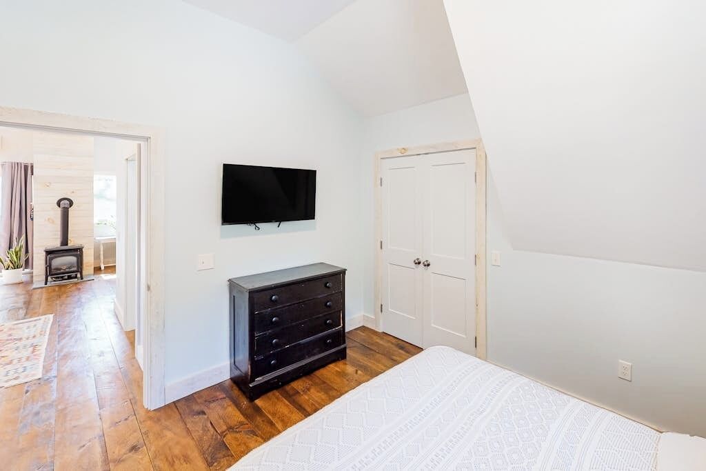 Ein Schlafzimmer mit Bett, Kommode, Fernseher und Tür.