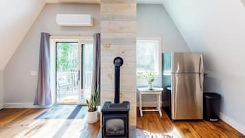 A room with a wood-burning stove, a stainless steel refrigerator, and a sliding glass door leading to an outdoor area.