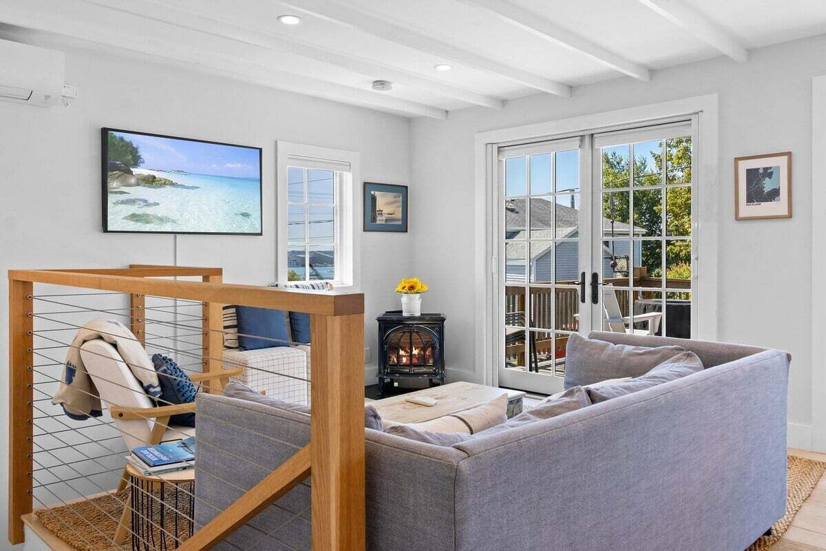 A living room with a sofa, a TV, a fireplace, and large windows.