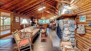 Ein Blockhaushaus-Interieur mit Kamin aus Stein, Holzmöbeln und einer Steinwand.