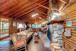 A log cabin interior with a stone fireplace, wooden furniture, and a stone wall. - Stunning log Cabin With Fireplace & Nature Views - Near Shopping & Dining (Boothbay Harbor)