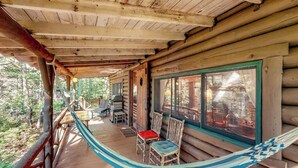 Eine Blockhütte mit Veranda, Sitzgelegenheiten im Freien und einer Hängematte.