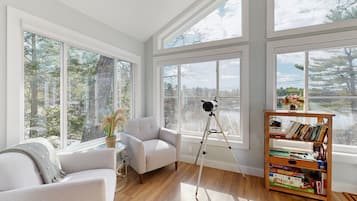 A room with large windows, a tripod, and a bookshelf.
