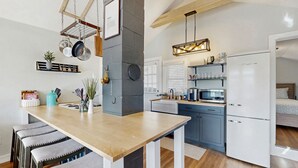Uma cozinha moderna com mesa de madeira, banquetas de bar, um suporte para panelas pendurado e forno embutido.