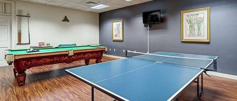 Una habitación con mesa de ping pong, mesa de billar y dos obras de arte enmarcadas en la pared.