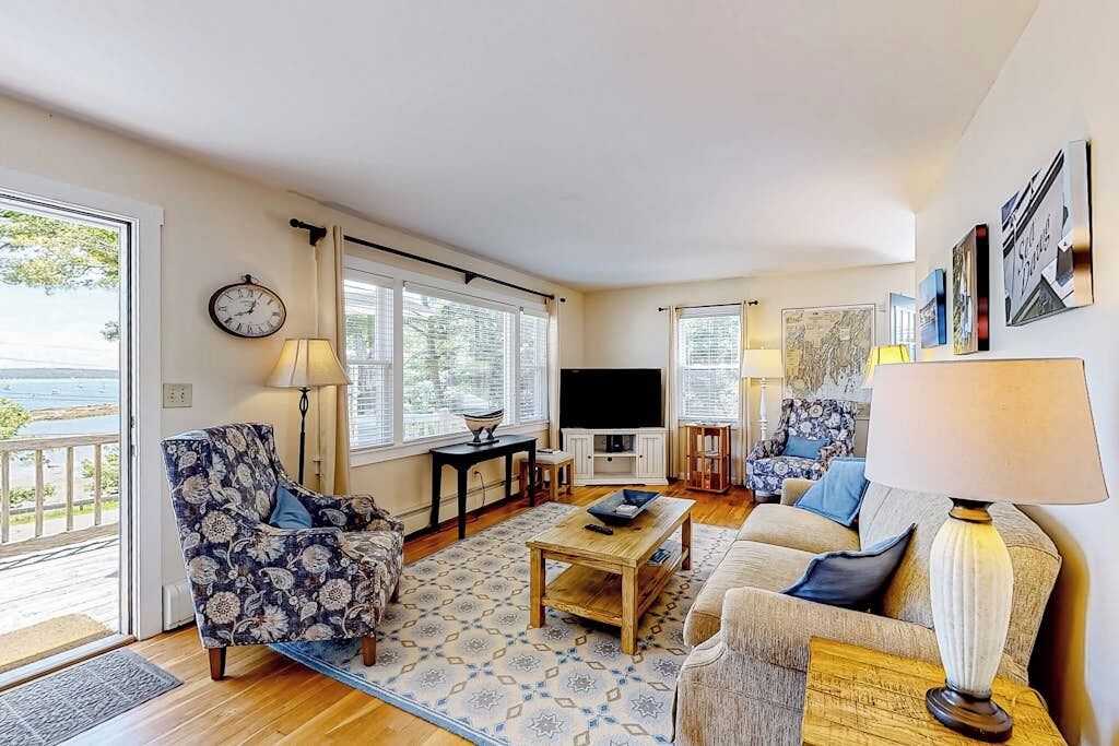 Una sala de estar con sofá, sillón, mesa de centro, televisor y ventana con vistas.