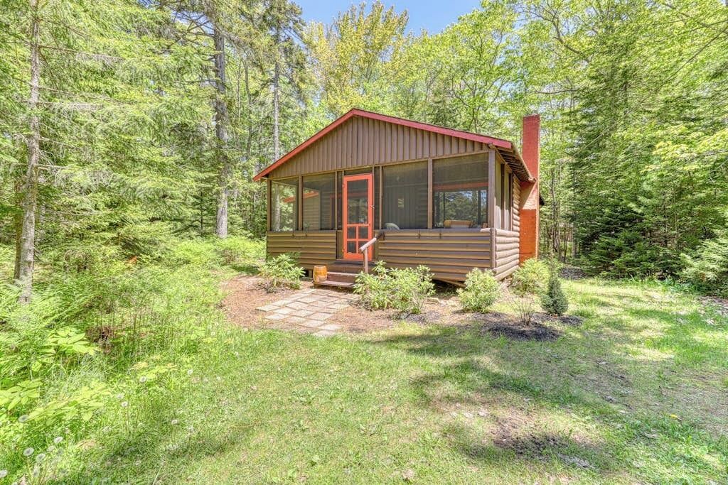 A cabin with a porch, a chimney, and a screened porch area.