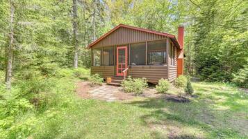 A cabin with a porch, a chimney, and a screened porch area.